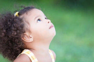 Small hispanic girl with an afro hairstyle looking up with space